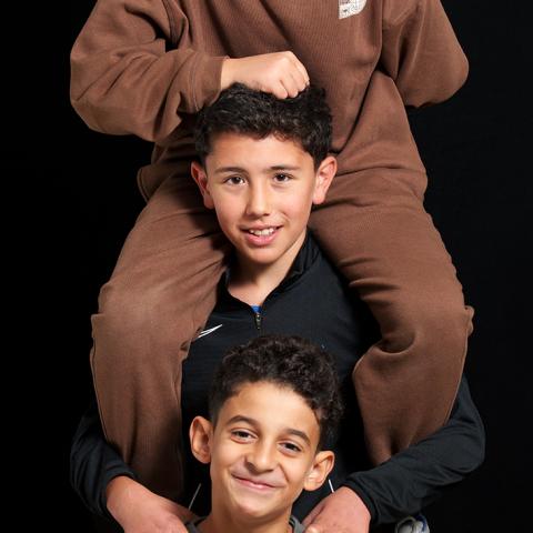 Portret van drie jongens die boven elkaar staan, de bovenste jongen zit in de nek van de jongen in het midden