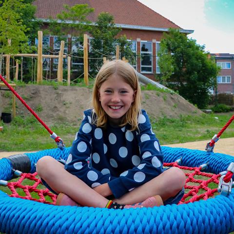 Een meisje op een speeltoestel aan speelplein 't Hofke