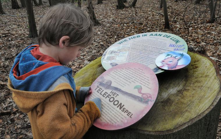 Een kind leest een informatiebord tijdens de wandeling op het spotterpad in het Tivolipark.