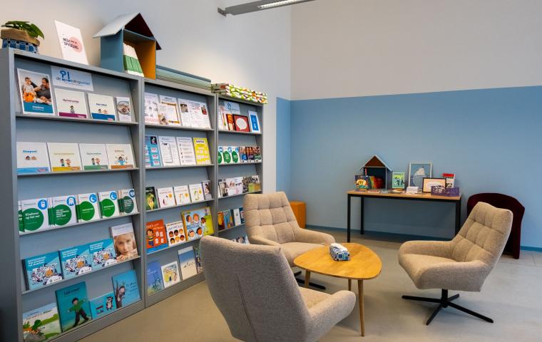 De opvoedingswinkel binnenin met zetels en rekken met infobrochures.