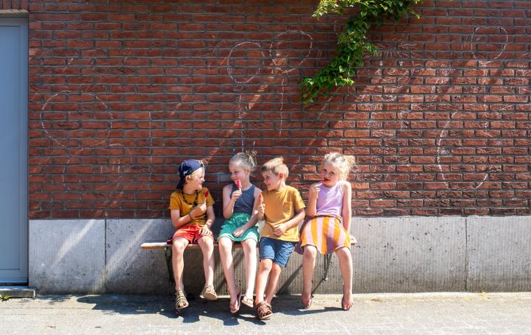 Kinderen zitten een ijsje te eten op een gevelbank.
