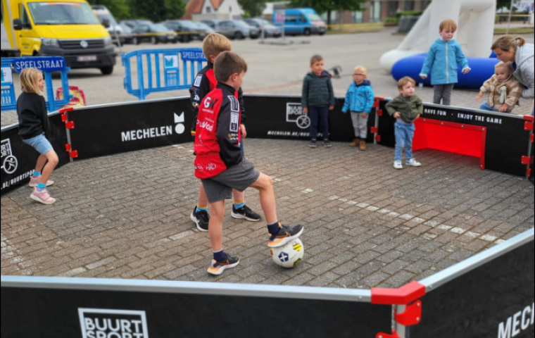 Kinderen voetballen in een kleine PCV pannakooi