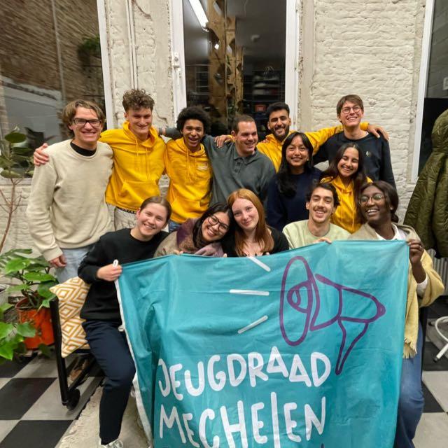 De leden van de jeugdraad poseren voor een vlag van de Jeugdraad.