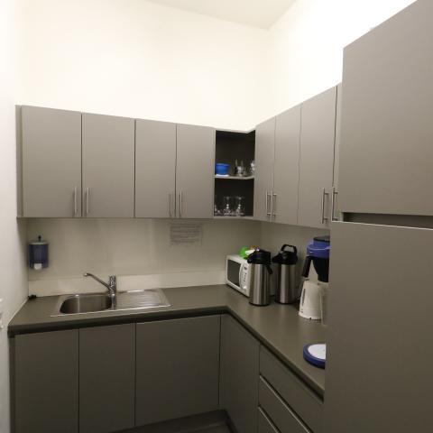 Kleine keuken met microgolf, koffiezet, waterkoker en wasbak.