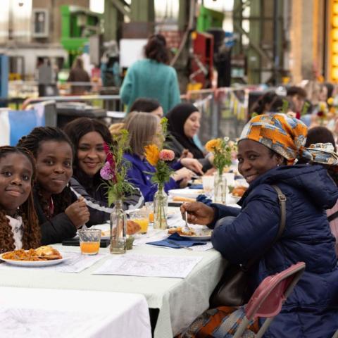 Mensen die in de camera lachen tijdens de wijkbrunch in de NMBS-loods in Wijk Arsenaal