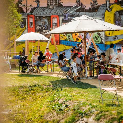 Tafeltjes aan de zijlijn van het speeltuintje zijn gevuld met mensen, buggy's, parasols tegen de zon ... 