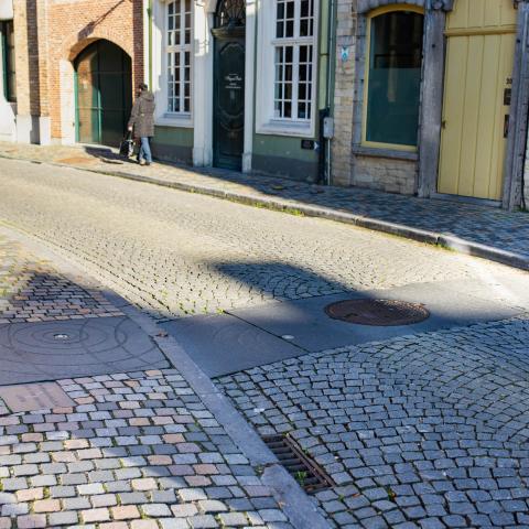 Een tegel met afdrukken van vallende druppels (verschillende cirkels). Dit toont aan dat er een vliet onder de straat loopt.
