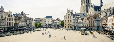 Zicht op de grote markt van Mechelen met de Sint-Romboutstoren op de achtergrond.