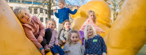 Kindjes spelen op de grote gele Opsinjoor onder den toren.