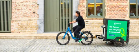 Een fietser met aanhangwagen van een leverbedrijf fietst voorbij het Predikheren.