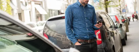 Een man betaald zijn parkeerticket via SMS